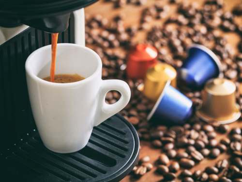 Vodič za pametnu kupovinu aparata za kafu - kapsule i zrna kafe na stolu