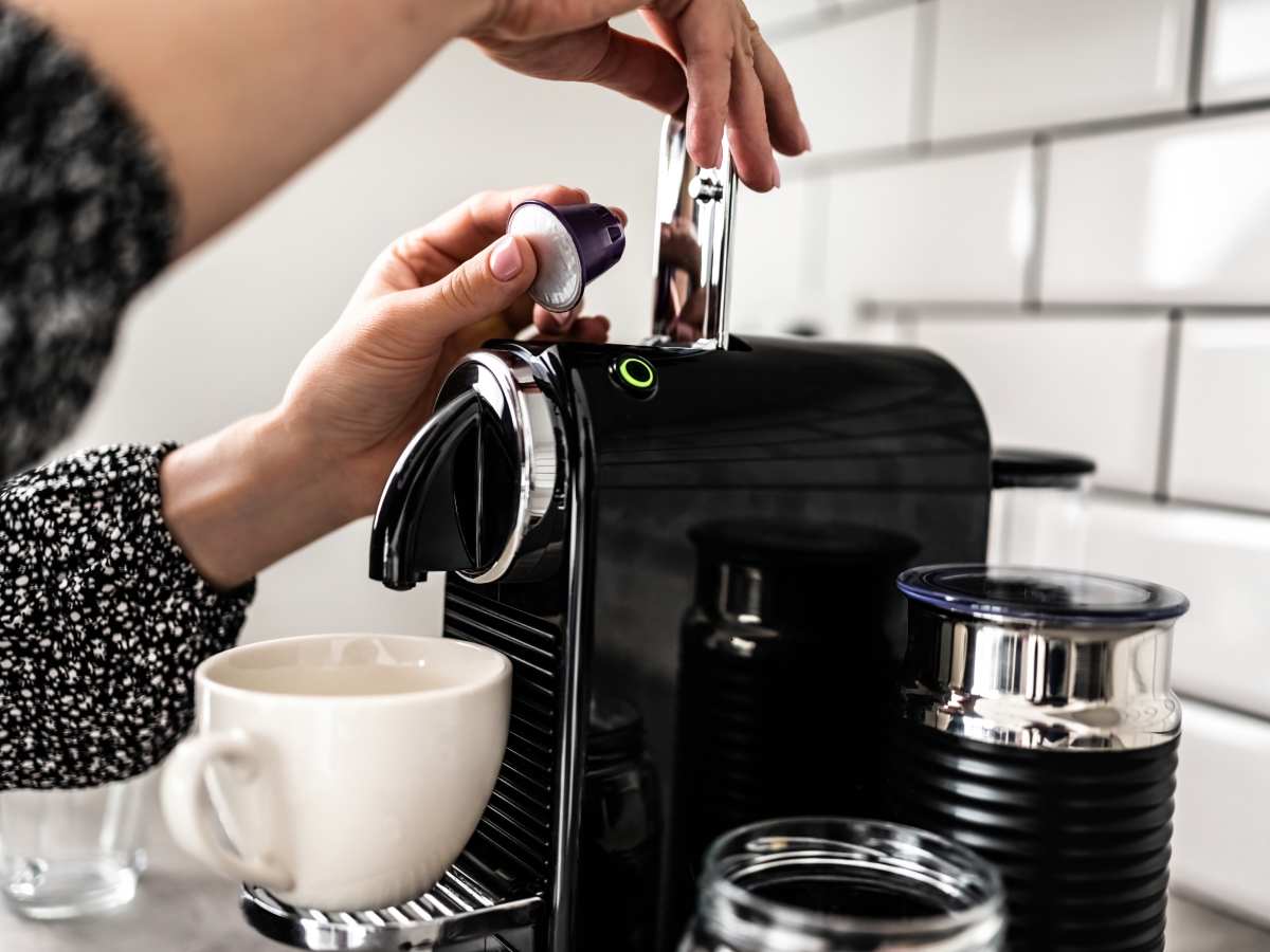 Ženska osoba ubacuje kapsulu u aparat za kafu