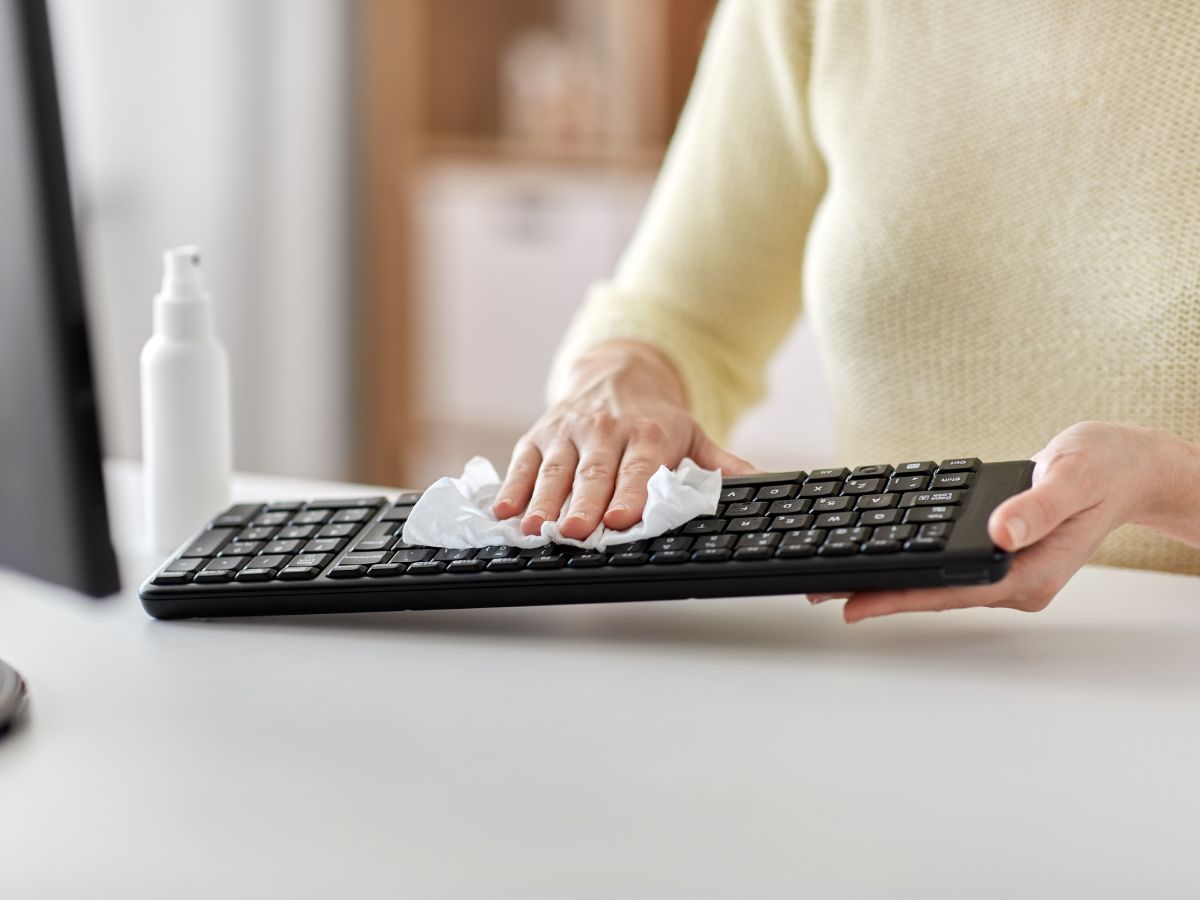 Ženska osoba briše tastaturu mikrofiber krpom