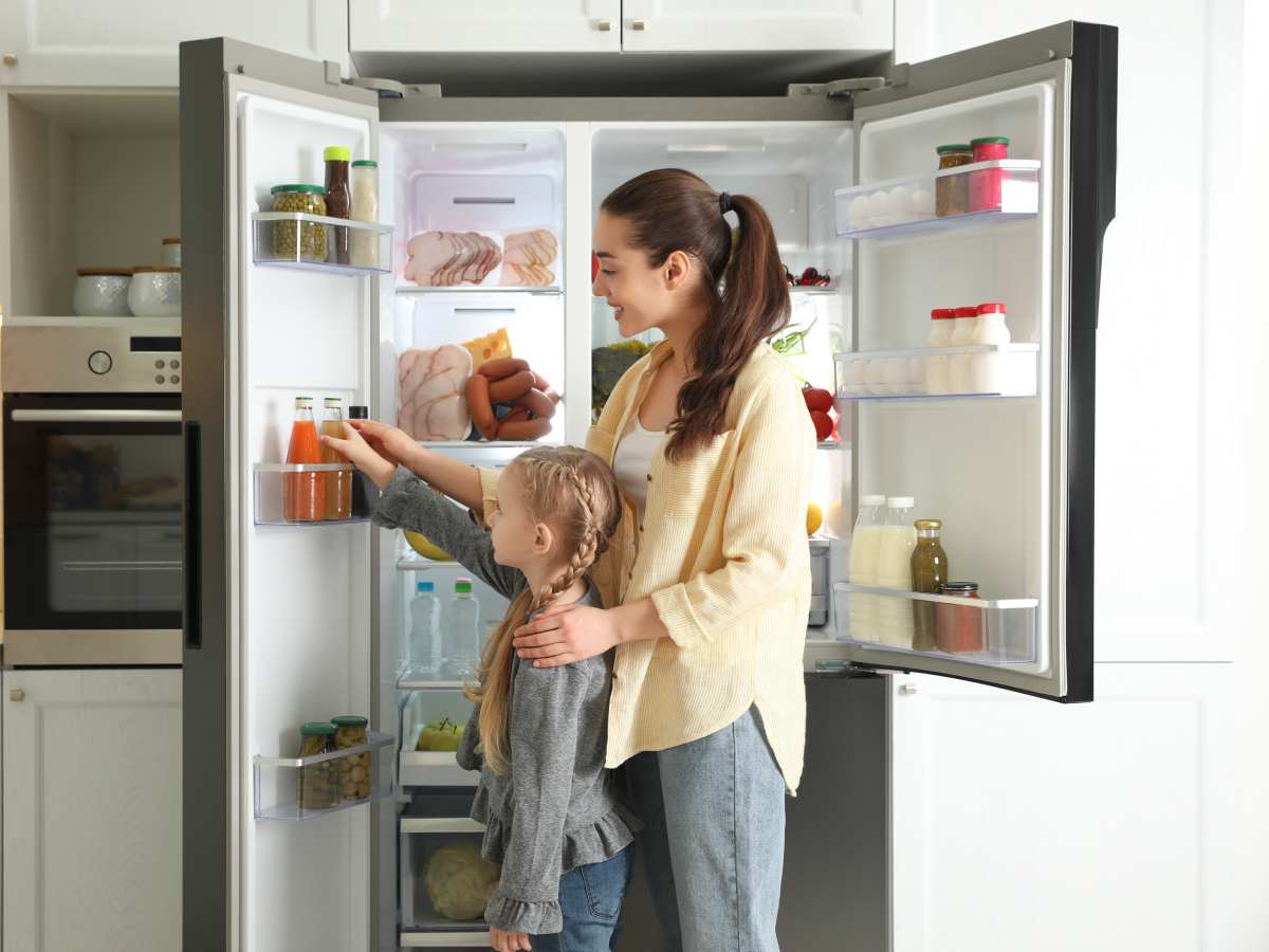 Majka i dete ispred otvorenog side-by-side frižidera