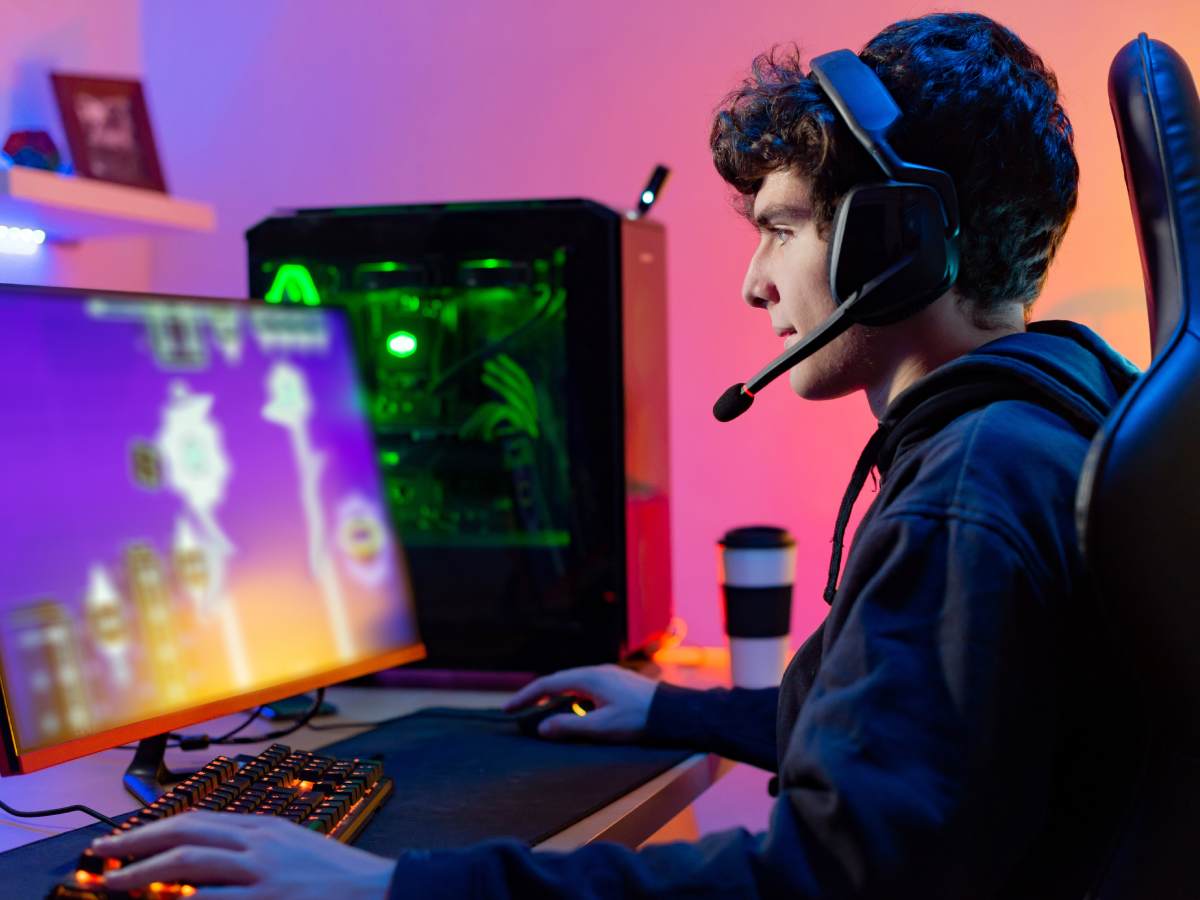 Gejmer ispred računara, sa gaming slušalicama na glavi