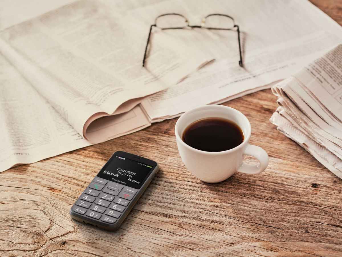 Panasonic KX-TU160E telefon, šolja kafe i naočare na stolu