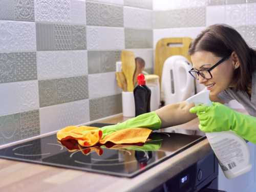 Kako očistiti ravnu ploču na šporetu ili ugradnu ploču za kuvanje - žena čisti ravnu ploču šporeta