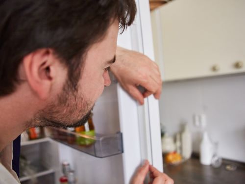 Kako da omekšate gumu na vratima frižidera ili zamrzivača - muškarac popravlja gumu na frižideru