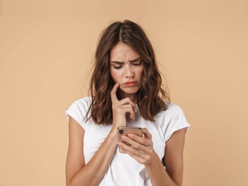 Kako saznati ko je vlasnik mobilnog broja telefona - devojka drži telefon u ruci i gleda u nepoznat broj na ekranu