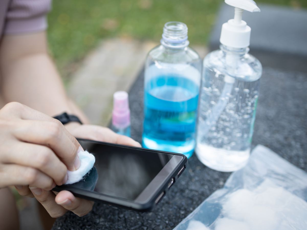 Sredstva za čišćenje mobilnih telefona i muška osoba koja čisti telefon vatom