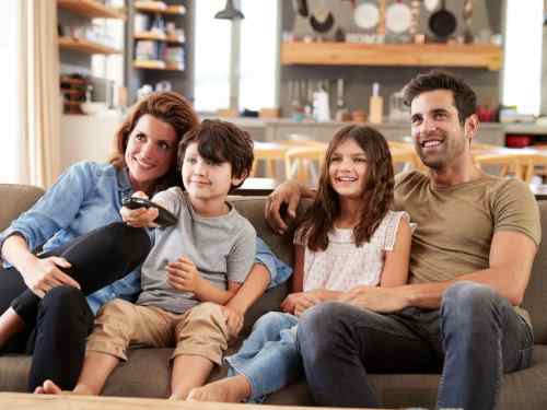 Kolika je idealna udaljenost od televizora - porodica sedi na kauču i gleda TV
