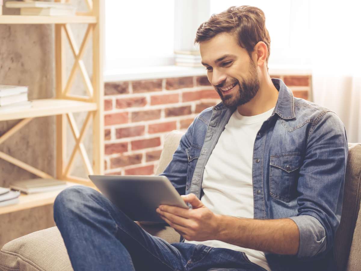 Muškarac sedi na fotelji i koristi tablet računar