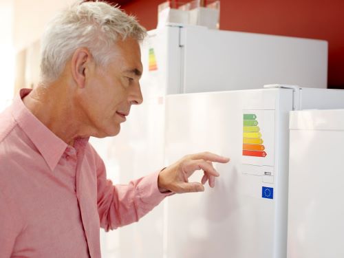 Šta je energetska klasa frižidera i kako utiče na to kolika je potrošnja frižidera - stariji čovek proučava karakteristike frižidera
