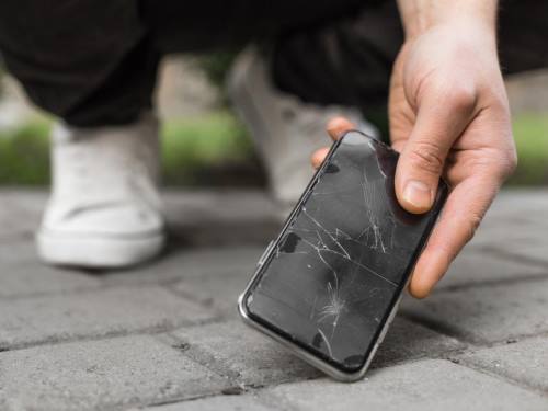 Šta obuhvata garancija za mobilne telefone - muškarac podiže telefon sa slomljenim ekranom, koji je pao na beton